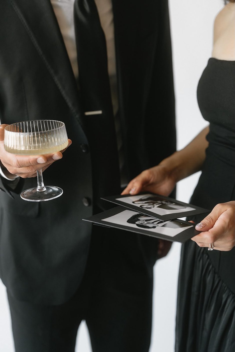 Hands holding photo booth prints beside a glass of champagne