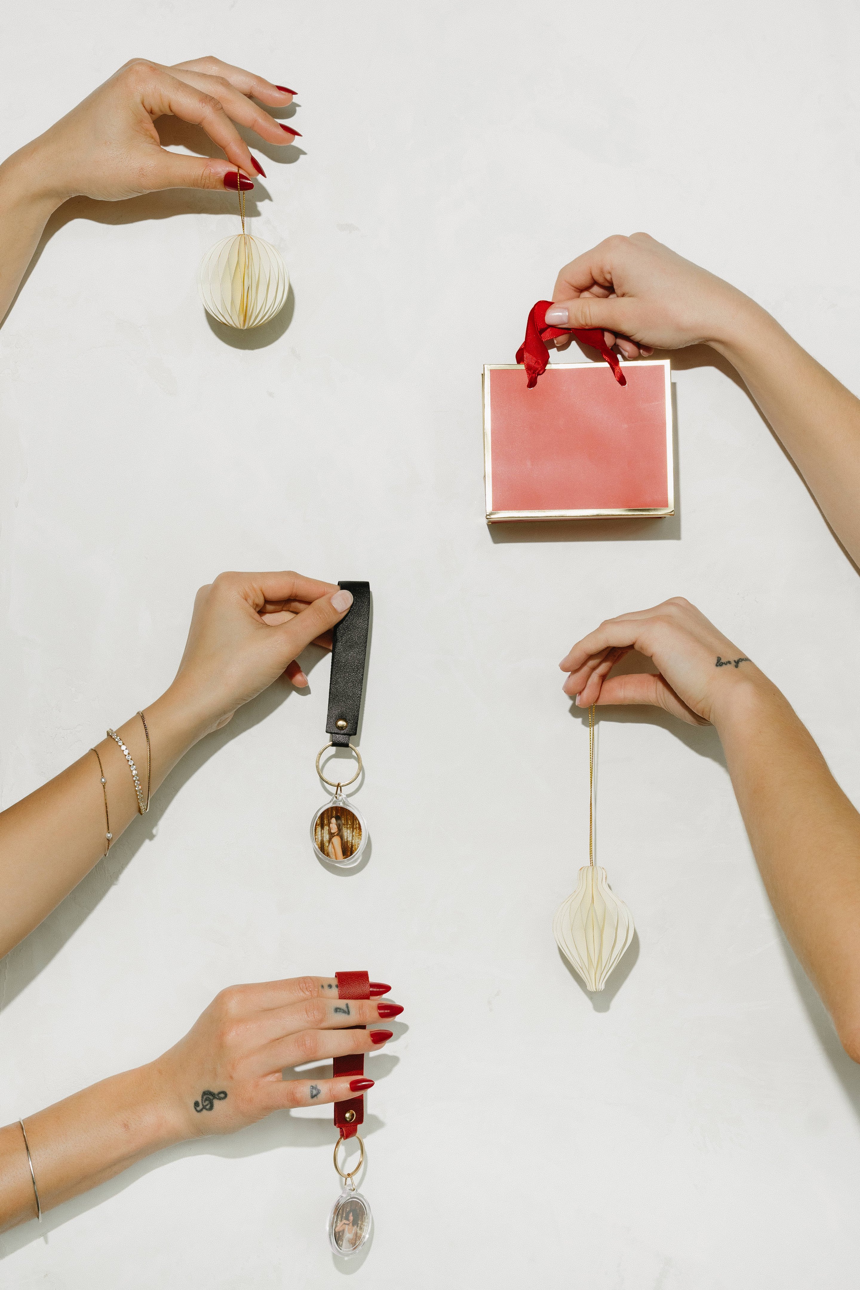 Hands holding photo keychains and a gift bag