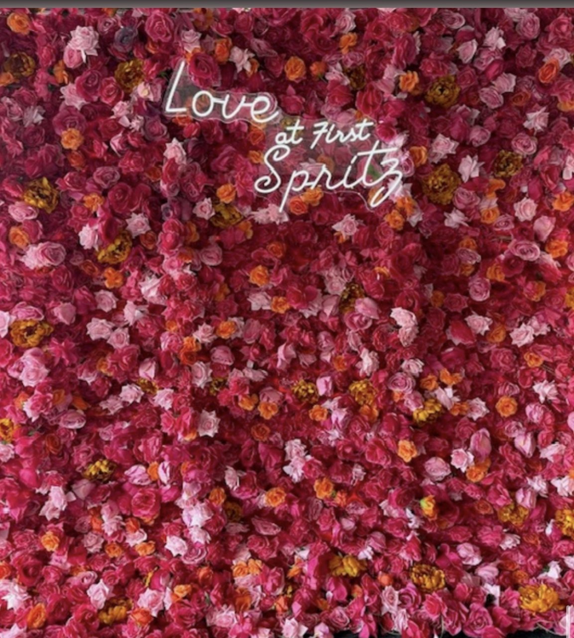 The Lady flower wall: pink, red and orange blooms, with a neon sign